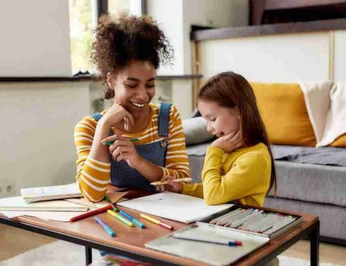 Caucasian little girl spending time with african american baby sitter. They are drawing, learning how to draw, sitting on the floor. Children education, leisure activities, babysitting concept