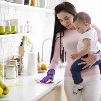 Domestic chores at maternity leave. Young mother with baby boy cleaning kitchen at home, free space